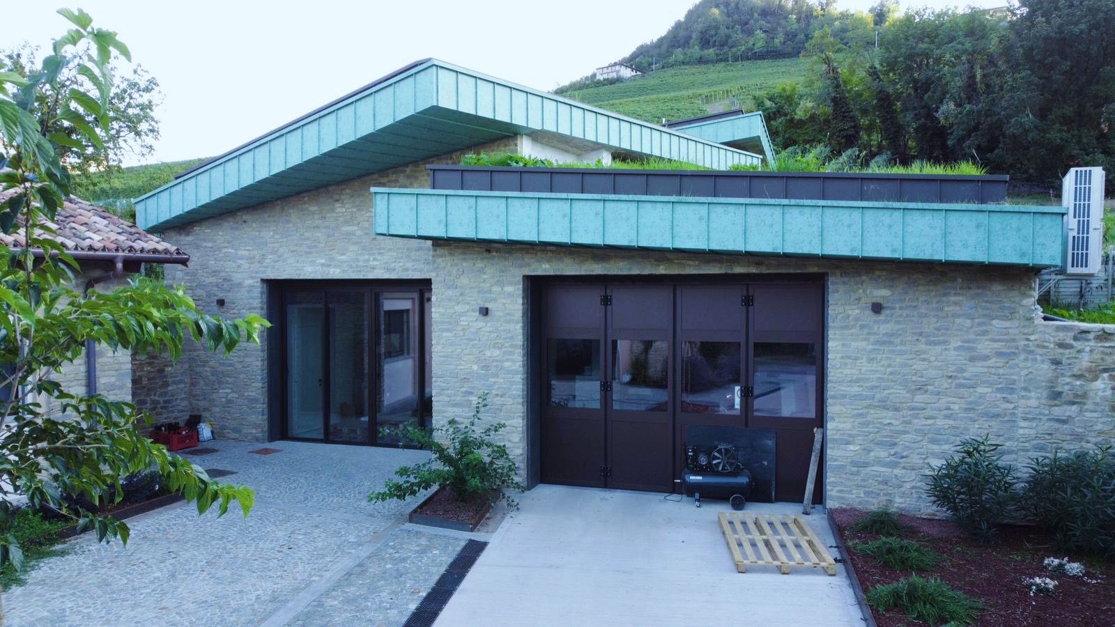 Copertura e sporti in rame patinato verde su edificio in pietra tra i vigneti