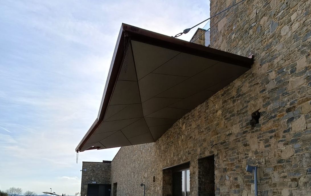 Pensilina rivestita in metallo su edificio in pietra